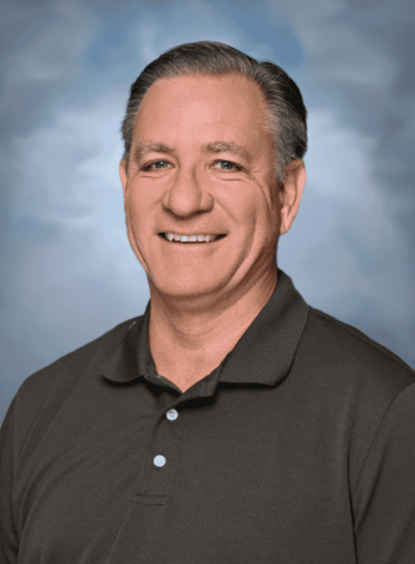 Professional headshot of a Springs Charter Schools staff member smiling in front of a soft blue studio backdrop.