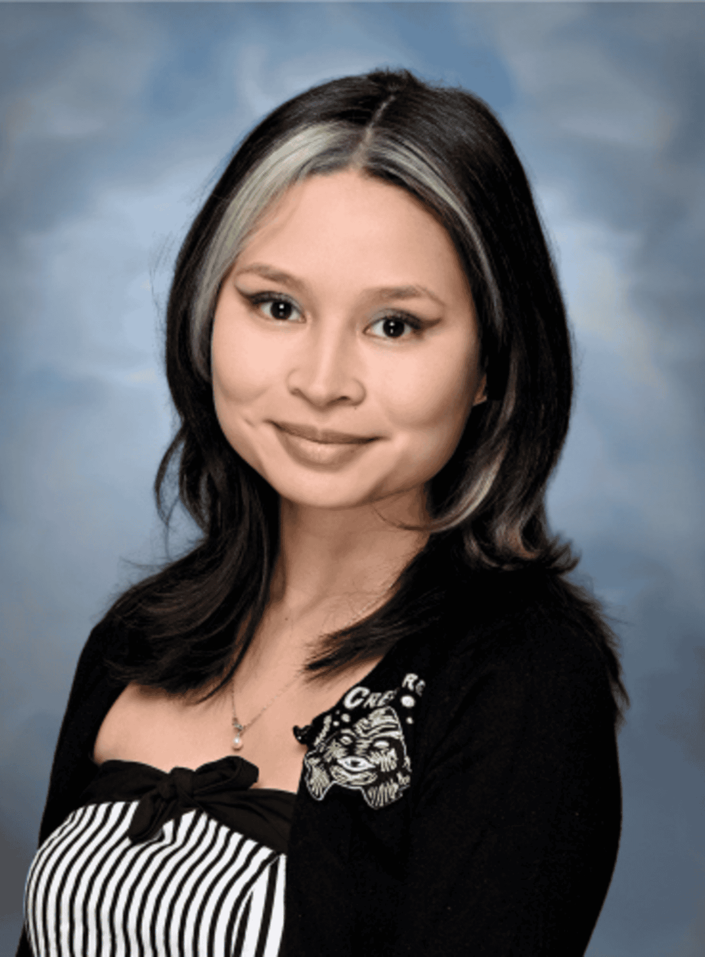 Professional headshot of a Springs Charter Schools staff member smiling gently in front of a soft blue studio backdrop.