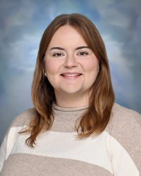 Portrait of staff member smiling against a studio background.