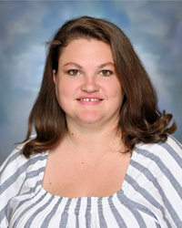 Portrait of staff member smiling against a studio background.
