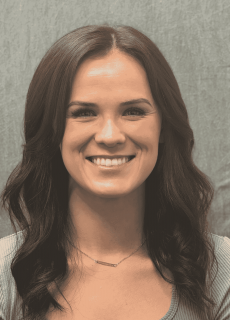 Headshot of a smiling woman with brown hair against a gray background