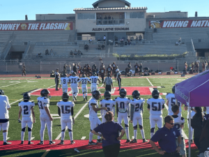 Springs Charter Schools football team and coaches pose together on the field under stadium lights after a night game.