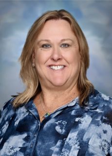 Professional headshot of a Springs Charter Schools staff member smiling in front of a soft blue studio backdrop.