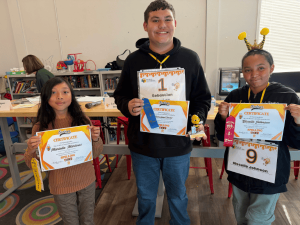 Springs Charter Schools students pose with certificates, ribbons, and a trophy after placing in the Spelling Bee.
