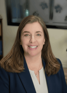 Smiling woman in a navy blazer and cream blouse in an office setting