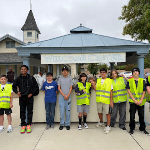 Group of students wearing safety vests standing in front of a Welcome Center during a community service activity.