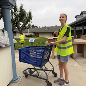 Student wearing a safety vest and pushing a cart during a community service activity at Springs Charter Schools.