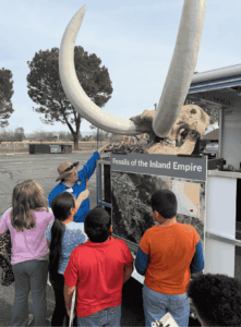 Students examining fossil specimens with a science instructor during a hands-on science lab activity.