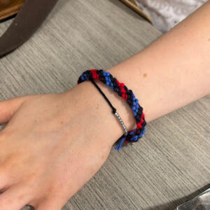 Close-up of a student’s wrist wearing a handmade red and blue braided bracelet created during a craft activity.