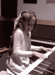Student playing a keyboard piano during a performance.