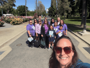 Group of staff and students wearing purple shirts posing together outdoors near a capitol building.
