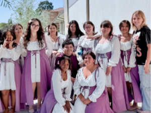Group of students wearing coordinated white and purple costumes posing together outdoors.