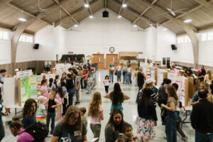 Families and students exploring science fair projects displayed throughout a large event hall.