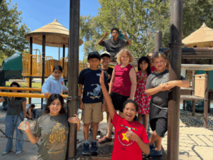 Elementary students smiling and playing together on a playground during an outdoor school activity.
