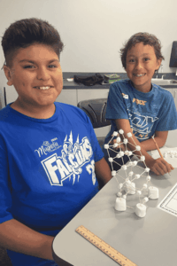 Students participating in a hands-on STEM activity using marshmallows and toothpicks to build a structure.