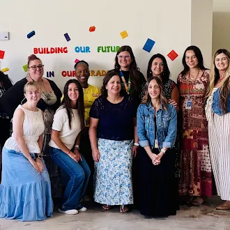 Hemet Learning Center staff members standing together in front of a colorful "Building Our Future" wall display at their new location.